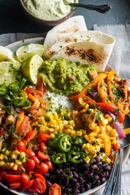 a bowl of chicken fajitas and fluffy rice with a mix of veggies like tomatoes and jalapenos, black beans, and corn