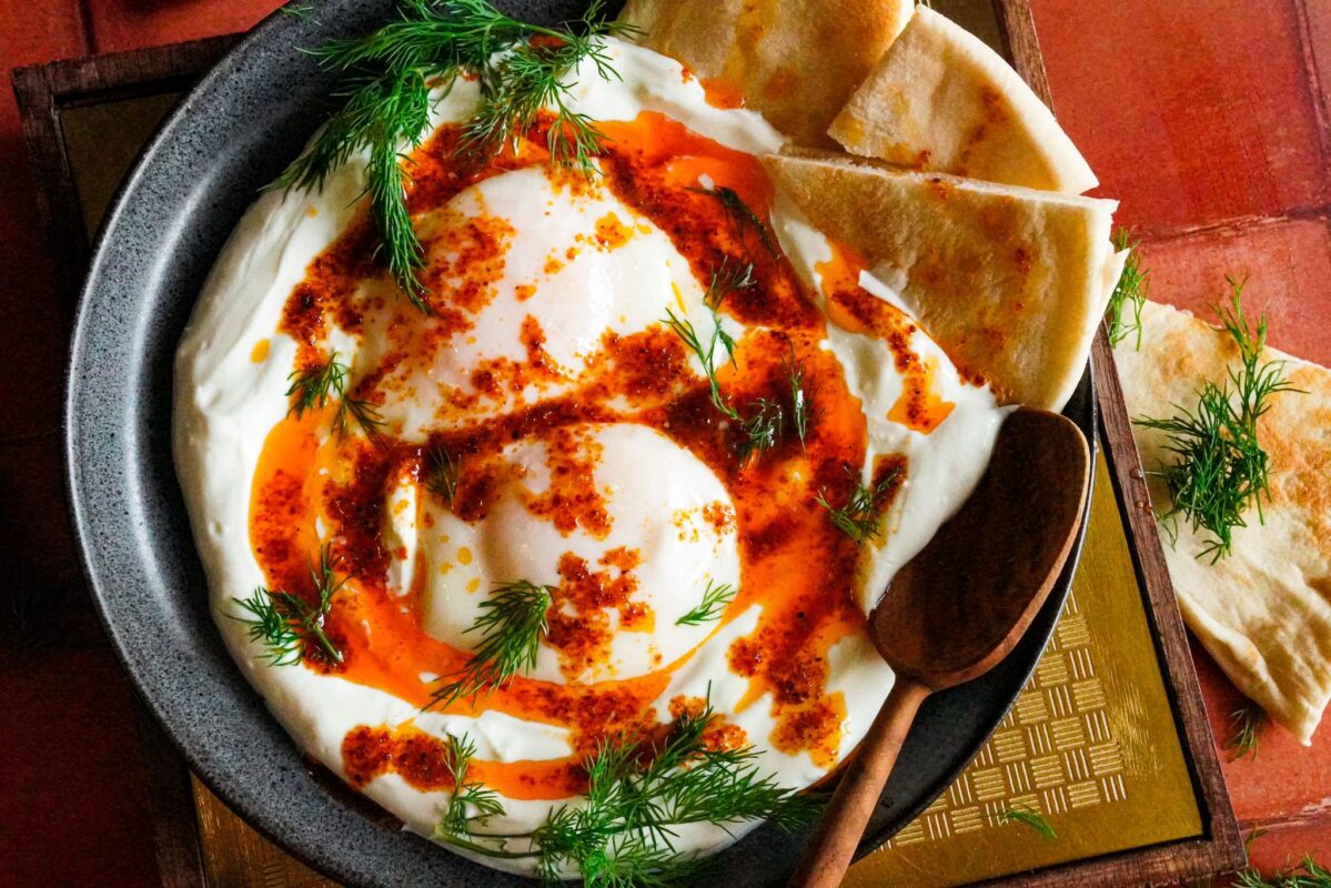 a plate of Turkish çilbir served with pita bread and sprinkled with a generous amount of chopped fresh dill