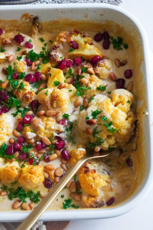 Perfectly made baked Cauliflower with tahini and topped with pomegranate, fried nuts, and parsley. 