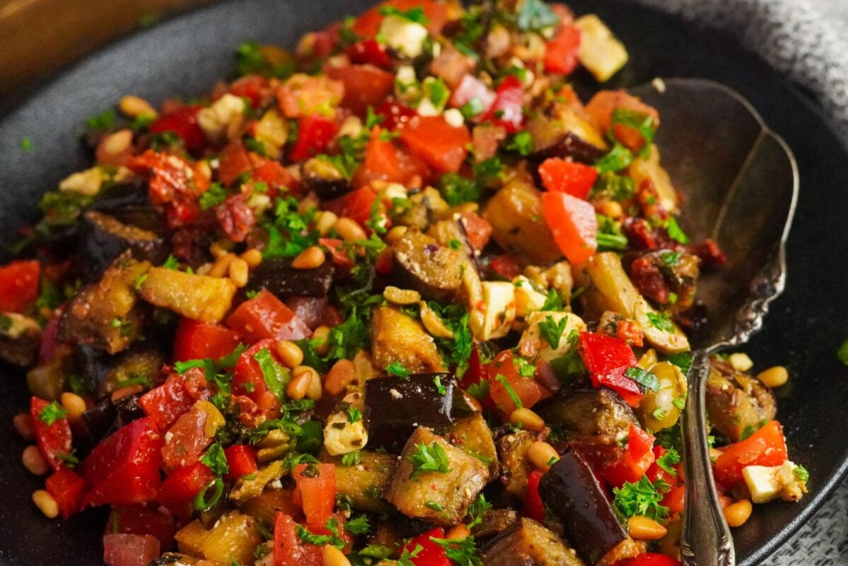 Traditional Eggplant Salad A delicious bowl of eggplant cubes, tomatoes, pine nuts, onions, and red onions seasoned with savory dressing made of sumac pomegranate molasses and other ingredients