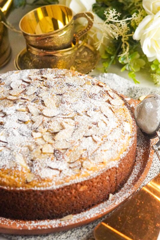 A delicious cake topped with sliced almonds and dusted with sugar