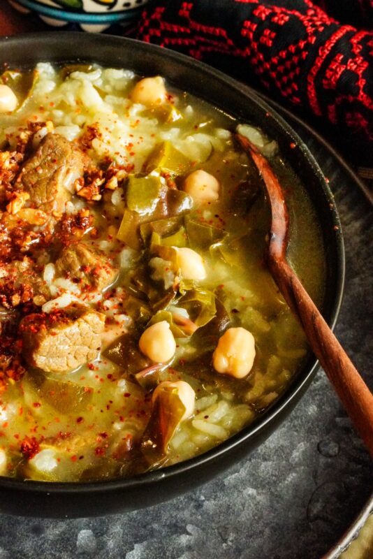 Palestinian fogaiyya stew in a bowl. The stew is made up of chickpeas, beef chunks, cooked rice, and Swiss chard.