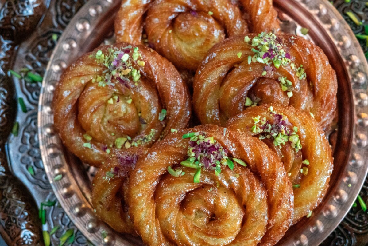 Middle Eastern Funnel cakes with pistachios and sugar sprinkled on top.