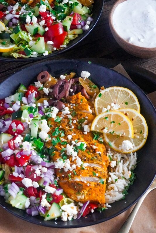 Greek Chicken Rice Bowl Recipe This healthy Greek chicken and rice bowl meal is served with feta cheese and lemon wedges on top and tzatziki sauce aside.