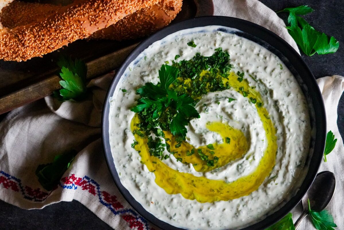 A top view of a bowl of huweirneh with a generous drizzle of extra virgin olive oil topped with finely chopped parsley and served with Palestinian sesame bread 