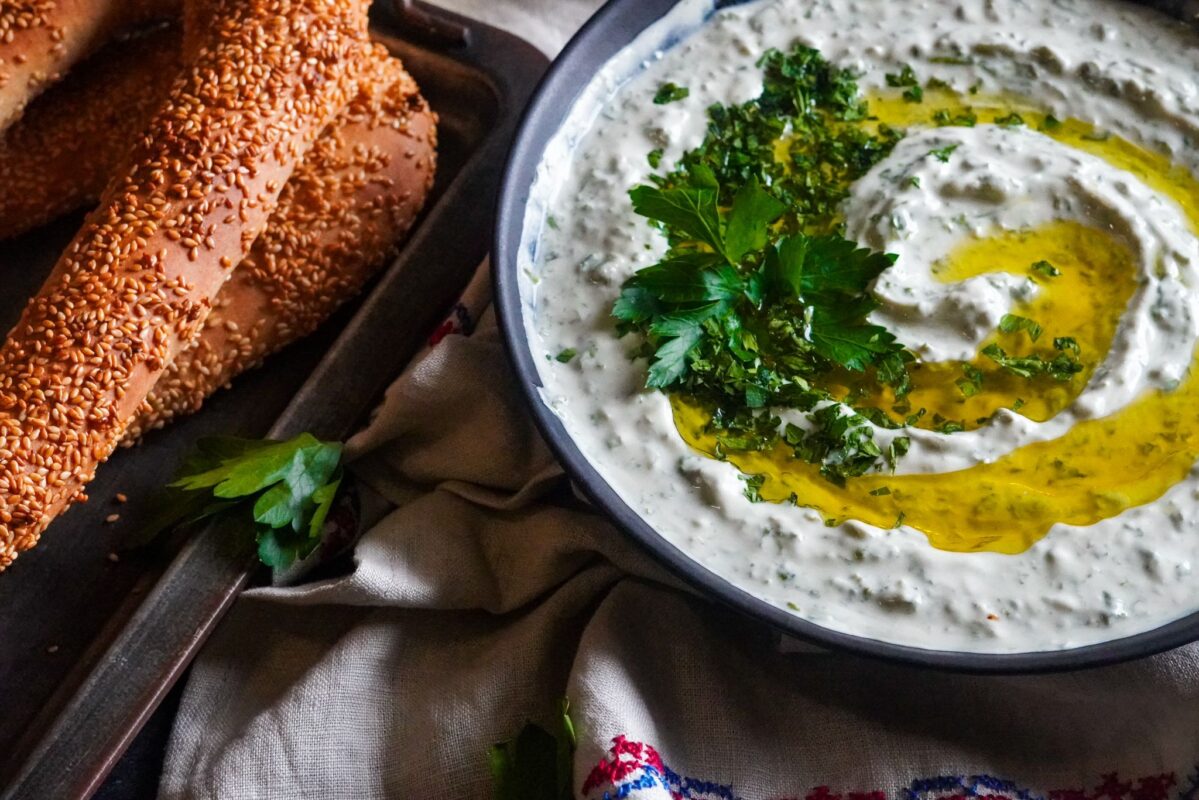 A bowl of huweirneh with a generous drizzle of extra virgin olive oil topped with finely chopped parsley and served with Palestinian sesame bread 