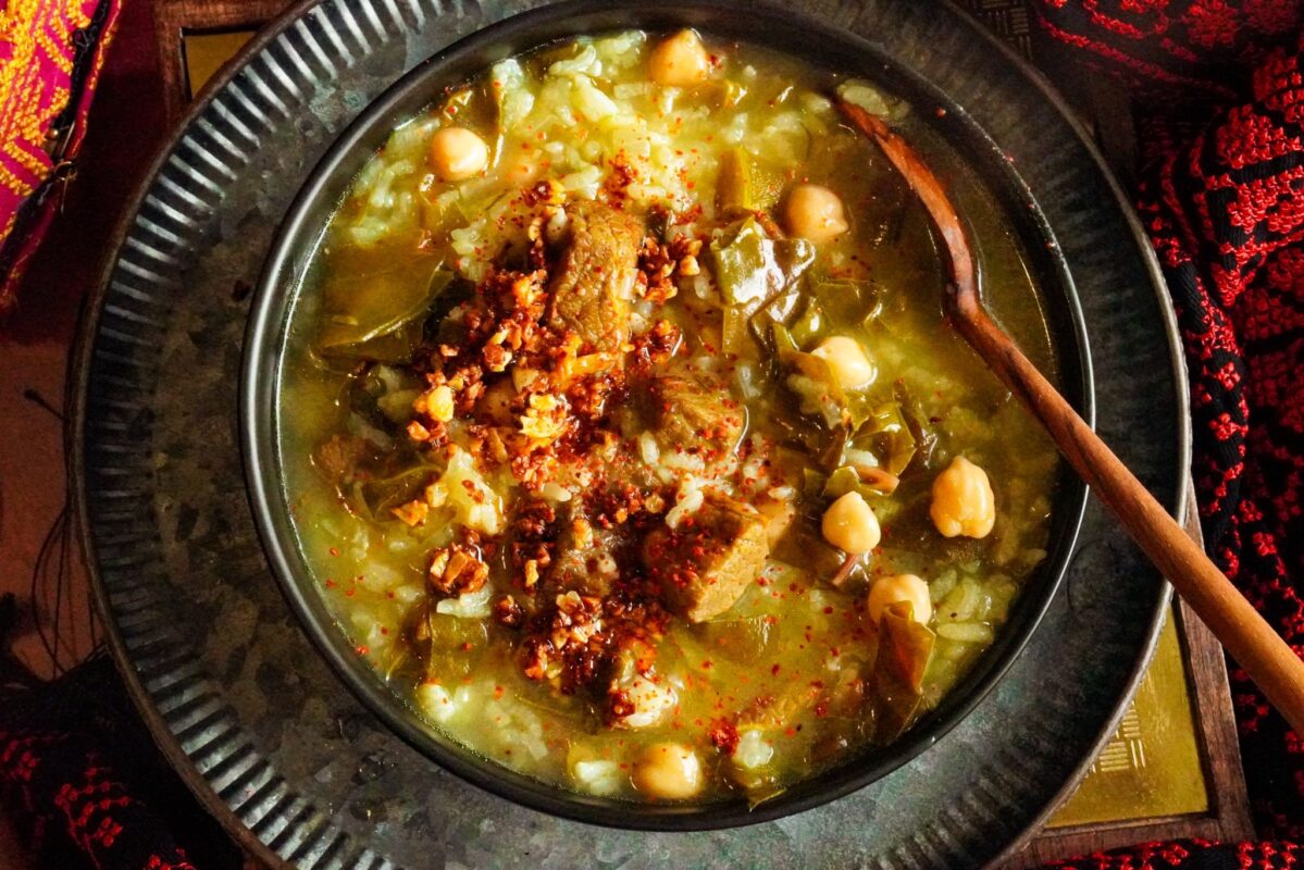 a bowl filled with Fogaiyya stew with beef chunks, Swiss chard, rice, chickpeas, and topped with shatta.