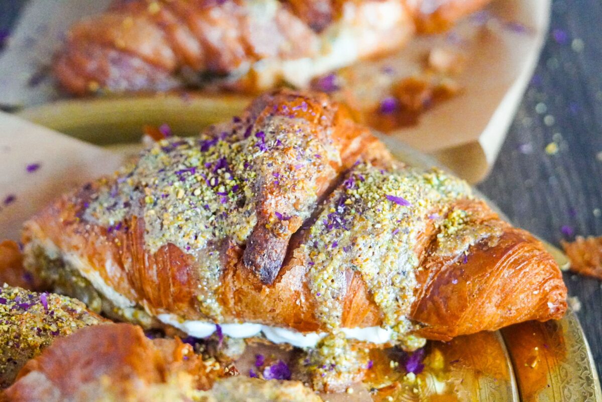 A large crispy croissant stuffed with Middle Eastern ashta and pistachio paste and topped with ashta and a sprinkle of ground pistachios