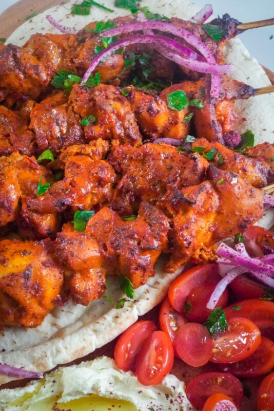 Zoomed in chicken on top of pita bread with bright red cherry tomatoes.