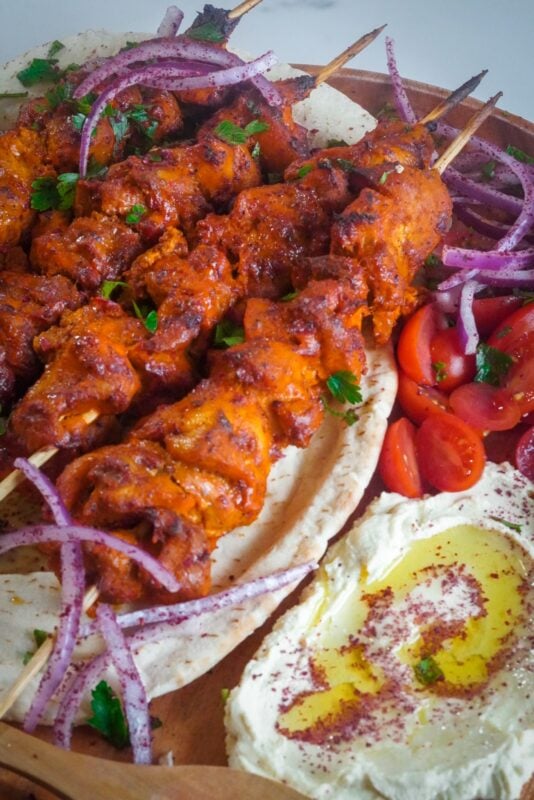 The chicken skewers are placed on top of pita bread garnished with parsley.