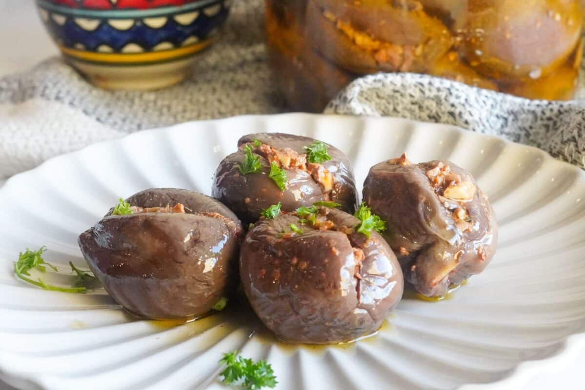 a plate contains four middle eastern stuffed eggplants pickles sprinkled with finely chopped parsley.