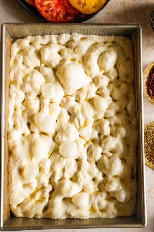 Bubbly focaccia dough placed in a baking pan.