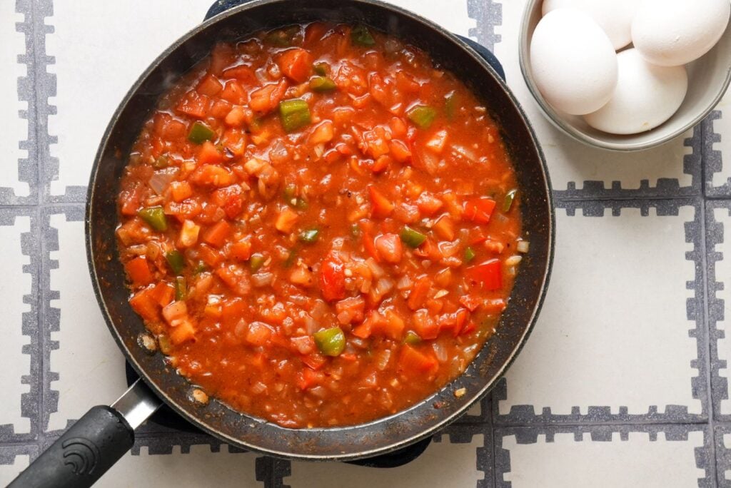 a pan of diced tomatoes and bell pepper simmered in tomato sauce