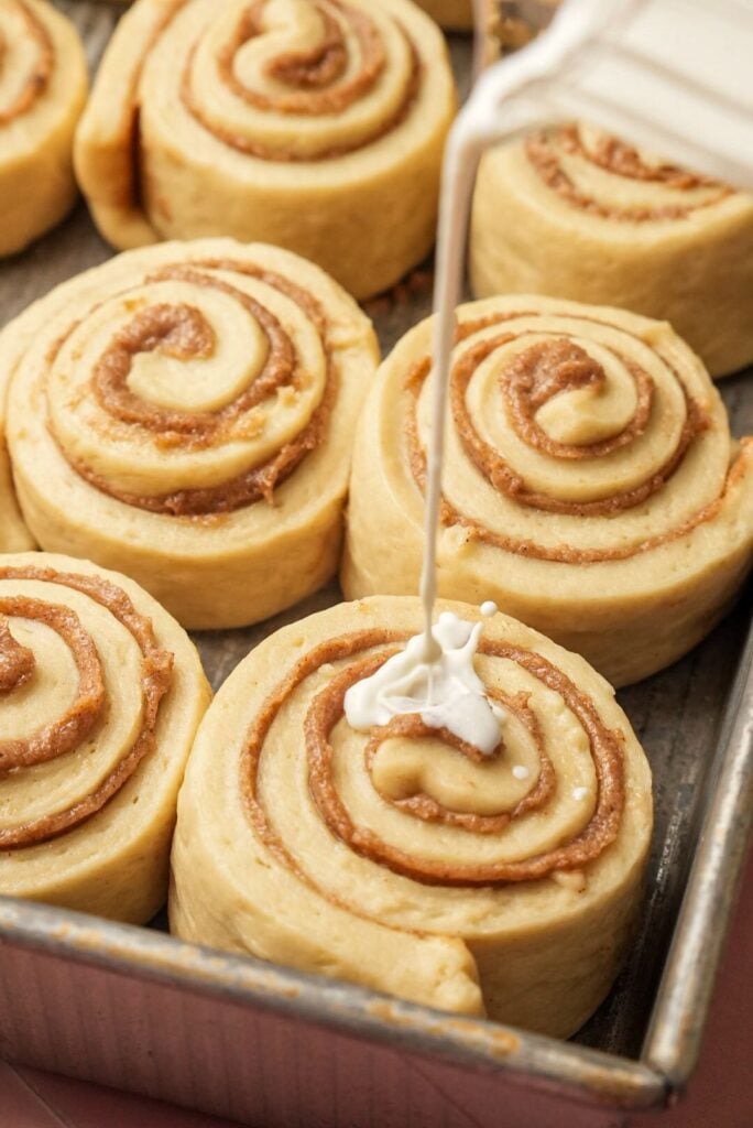 a shot of pouring warm heavy cream all over the cinnamon rolls before baking