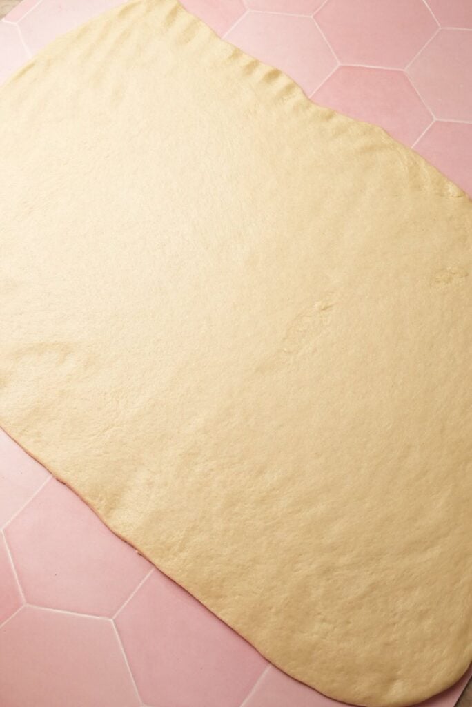 a shot of stretched dough into a large 12x18 rectangle with uneven edges trimmed off